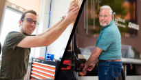 Twee mannen met bril, de een bouwt aan orgels de ander bij een vrachtwagen voor het transport van orgels