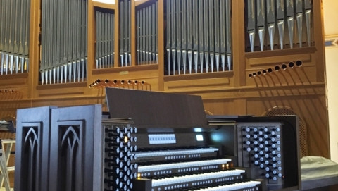 Een kerkorgel waarvan je de pijpen ziet en het orgel zelf met 4 lagen toetsen en alle registers